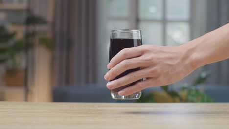 man hand place fresh cola in tumbler glass on table