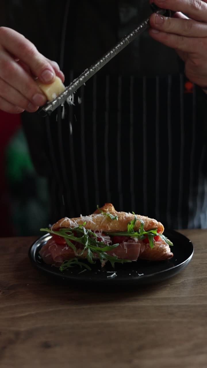 Preparing a Croissant Sandwich with Prosciutto, Arugula, and Cheese