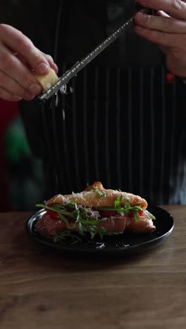 preparando un sándwich de croissant con jamón, rúcula y queso