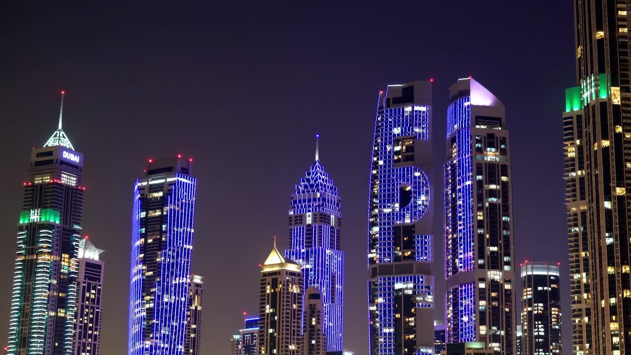 Dubai skyscrapers glowing against dark sky, reflecting architectural brilliance and urban energy with luminous high rise buildings dominating nighttime cityscape