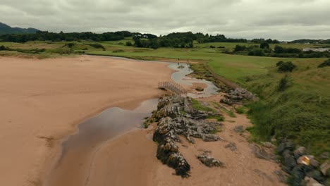 drones sobre la arena y los bunkers en los enlaces irlandeses campo de golf con calles verdes, cielo brumoso, tiro de establecimiento
