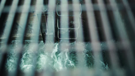 rushing flood water in sewer drainage overflow tunnel through metal grate