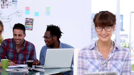 Cheerful-designer-posing-while-her-colleagues-are-working-together