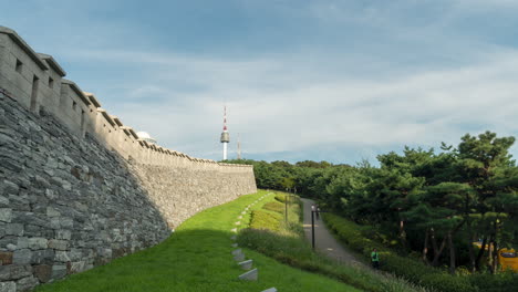 Gente-Caminando-Cerca-De-La-Muralla-De-La-Ciudad-De-Seúl-En-El-Parque-Namsan-Y-La-Torre-N-De-Seúl-En-La-Montaña-Namsan-En-El-Fondo-De-Corea-Del-Sur---Lapso-De-Tiempo-De-Verano