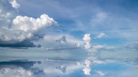 futuristic background consisting of time lapse clip of white fluffy clouds over blue sky and their reflection, video loop