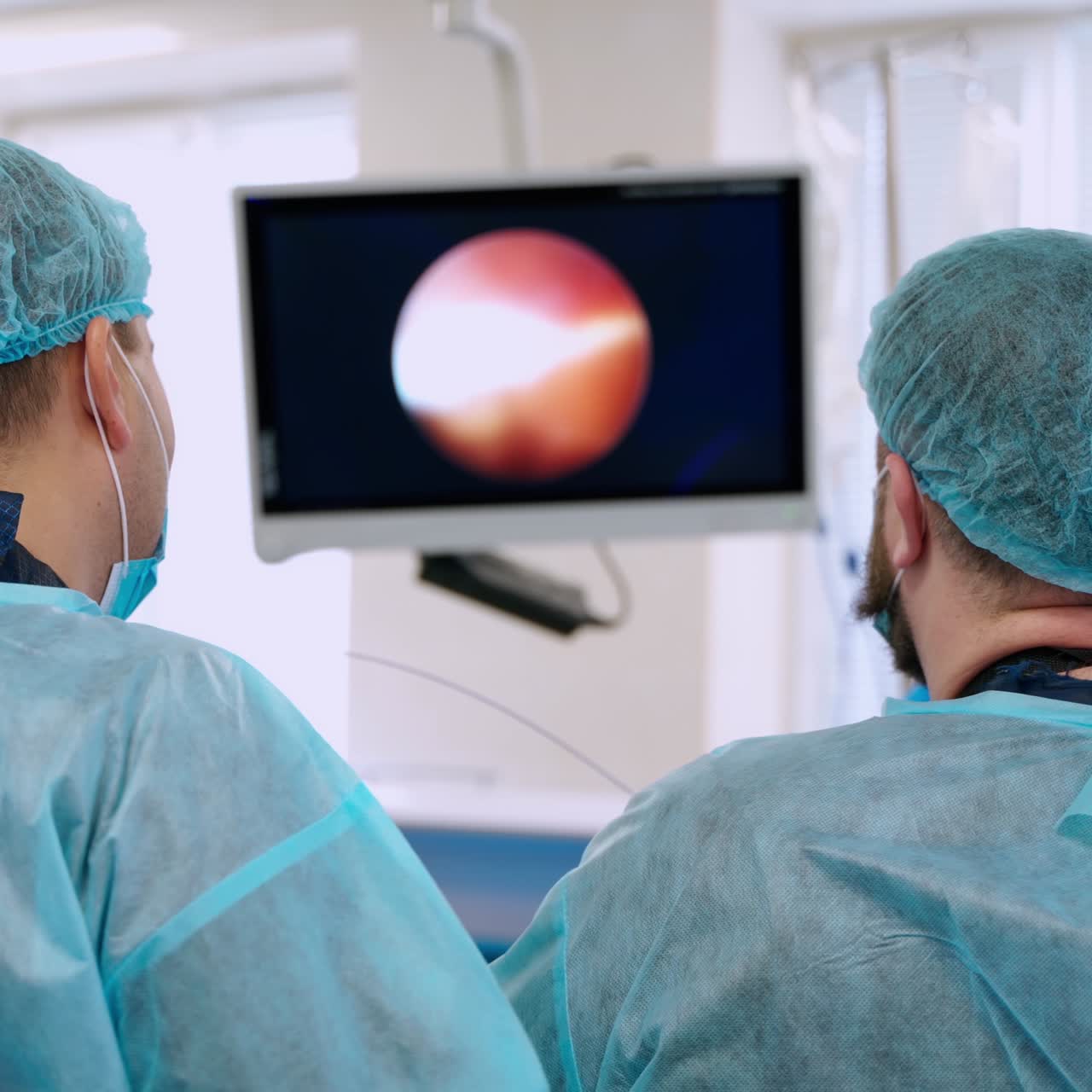 Laparoscopic operation in clinic. Backside view of surgeons in the operating room. Medical specialists perform a surgery using modern equipment.