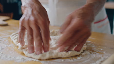 hands of senior woman flattening homemade dough on floured table