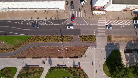 Aerial-view-of-city-intersection-with-cars,-pedestrian-pathways,-and-urban-landscaping