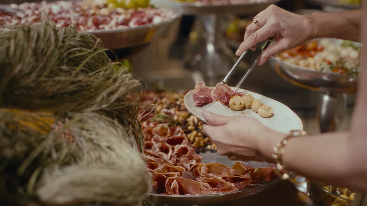 Mani scelgono salumi e olive da un sontuoso vassoio. Banchettare è un'esperienza gioiosa, sociale e sensoriale. Perfetto per immagini di matrimoni, feste o eventi gourmet