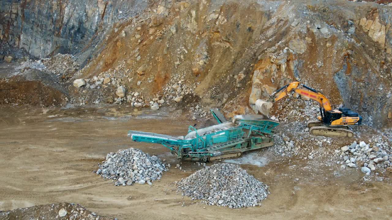 separación de roca y grava: vista aérea de una excavadora que alimenta una criba inclinada sobre orugas en una cantera minera