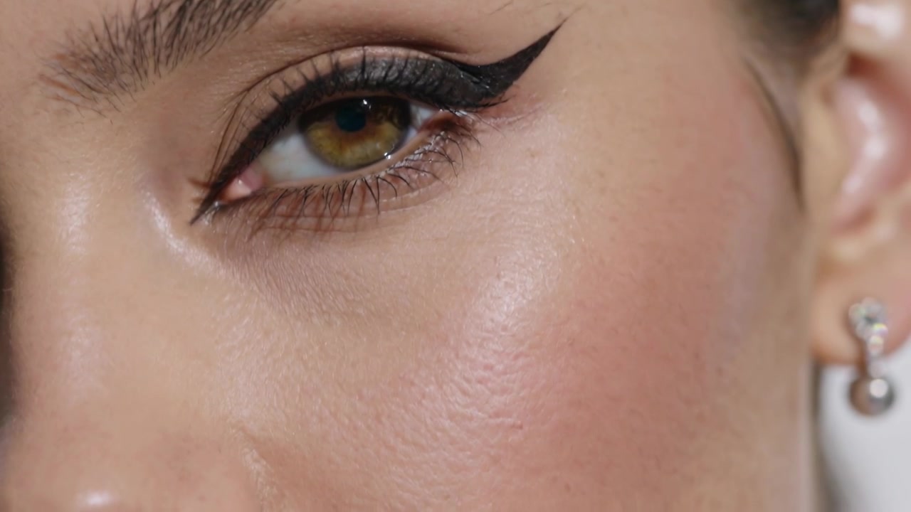 Revealing model shifting gaze as camera moving right and down at studio, showcasing winged eyeliner