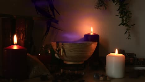 Detail-of-a-potion-making-witch-room,-with-purple-steam-coming-out-from-a-wooden-bowl,-animal-teeth-hanging-from-it,-candles-with-flickering-flames,-old-books,-glasses-and-herbs,-dust-flying-around