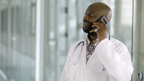 A-happy-African-American-male-doctor-is-talking-on-his-cell-phone