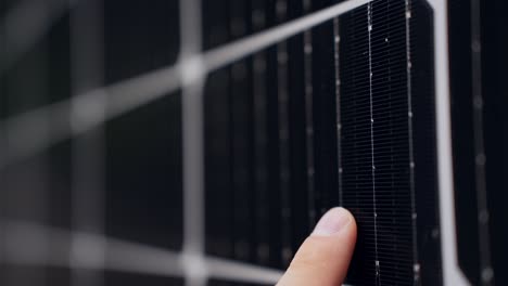 detail closeup of finger sliding on solar panel cell surface for inspection