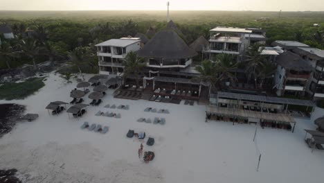 Aerial-zooming-view-of-Amansala-hotel-buildings-at-sunset-with-dense-jungle-in-the-background