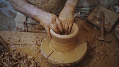 potter working red clay piece medium shot