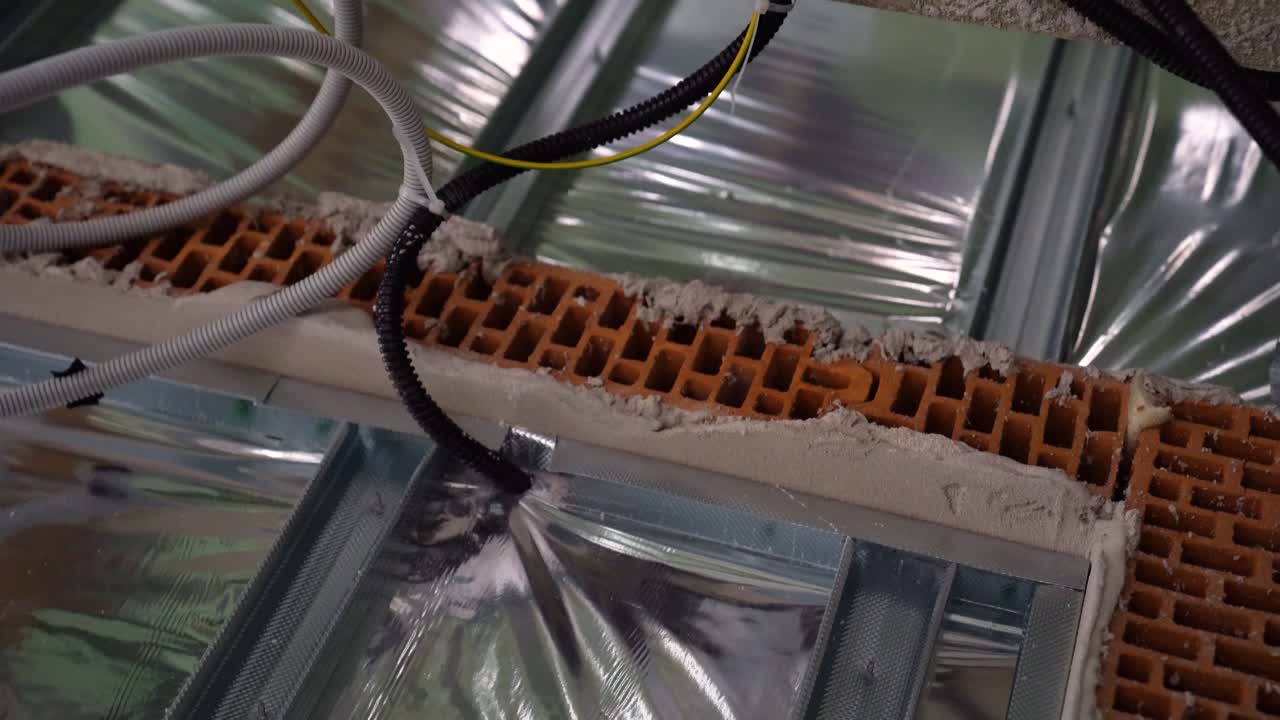 Close-up of brick and insulation layer with electrical conduit running through floor