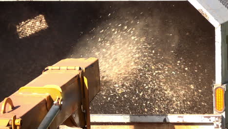 close-up of wood chips expelled from the chute of wood chipper into the back of a truck in slow motion