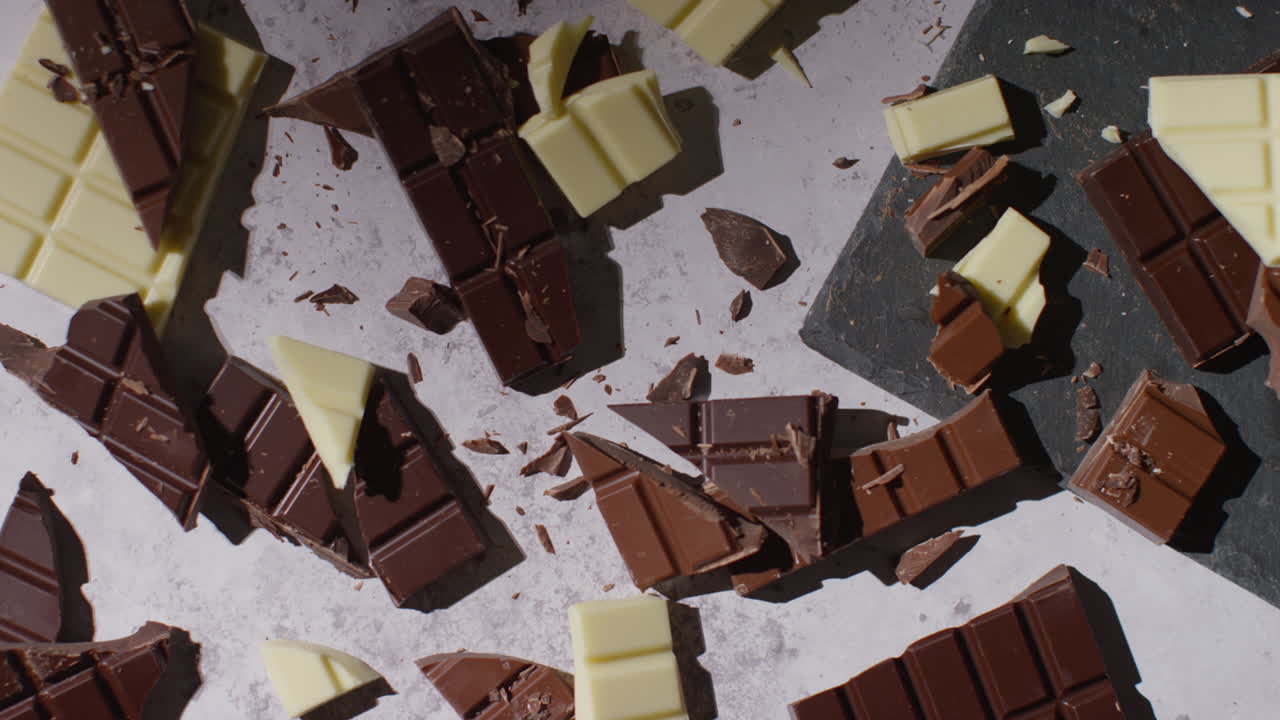 человек, поднимающий кусок из сломанных барок молока и белого шоколада