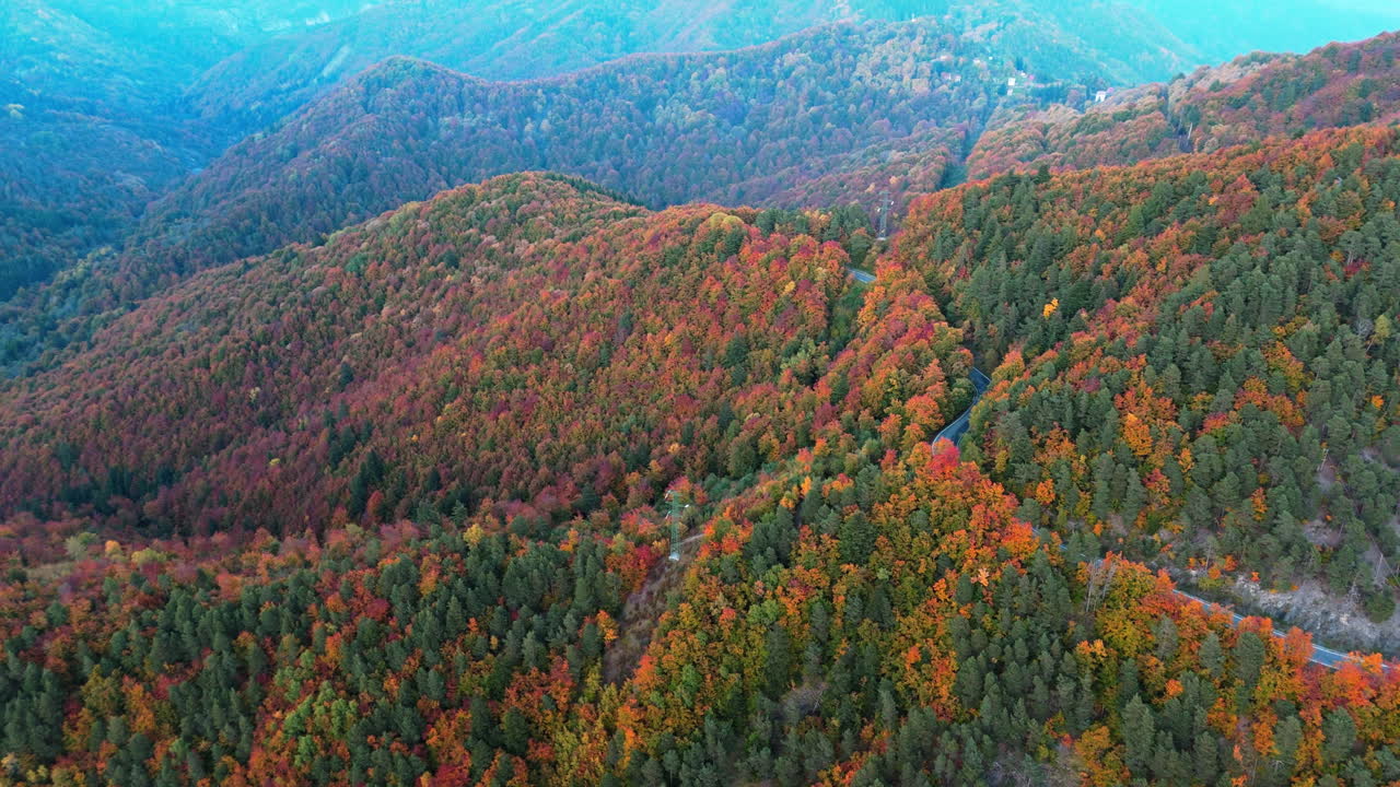 Aerial view of vibrant fall mountains with winding road, peaceful atmosphere