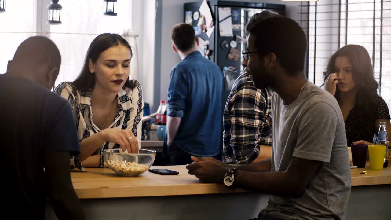 혼합된 민족의 친구들은 함께 어울리고 대화합니다. 다양한 캐주얼 젊은 그룹은 집에서 유대적인 대화 시간을 공유합니다.
