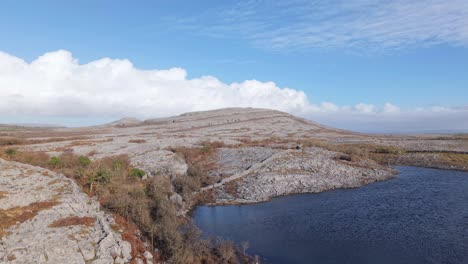 rocky limestone landscape with a lake in the burren, ireland, under a bright sky