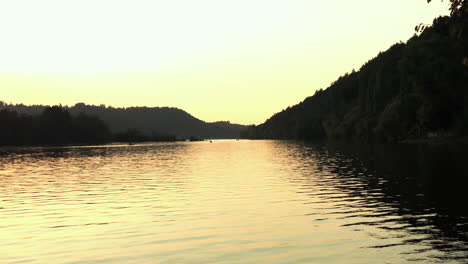 low angle view across the water's surface as the lake glows in golden light from the sunset