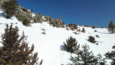 Aerial-view-flying-up-snowy-rocky-mountain,-Carson-Pass,-California