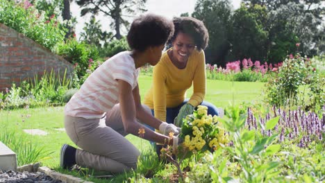 retrato de una madre y una hija afroamericanas sonrientes jardineras juntas en un jardín soleado