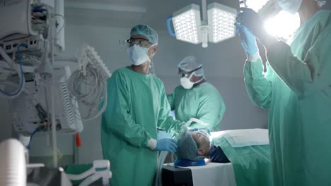 diversos cirujanos con máscaras faciales usando máscara de oxígeno en el paciente en la sala de operaciones en cámara lenta