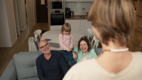 playful crazy young daddy performing parody to guess together with a family in living room, slow motion