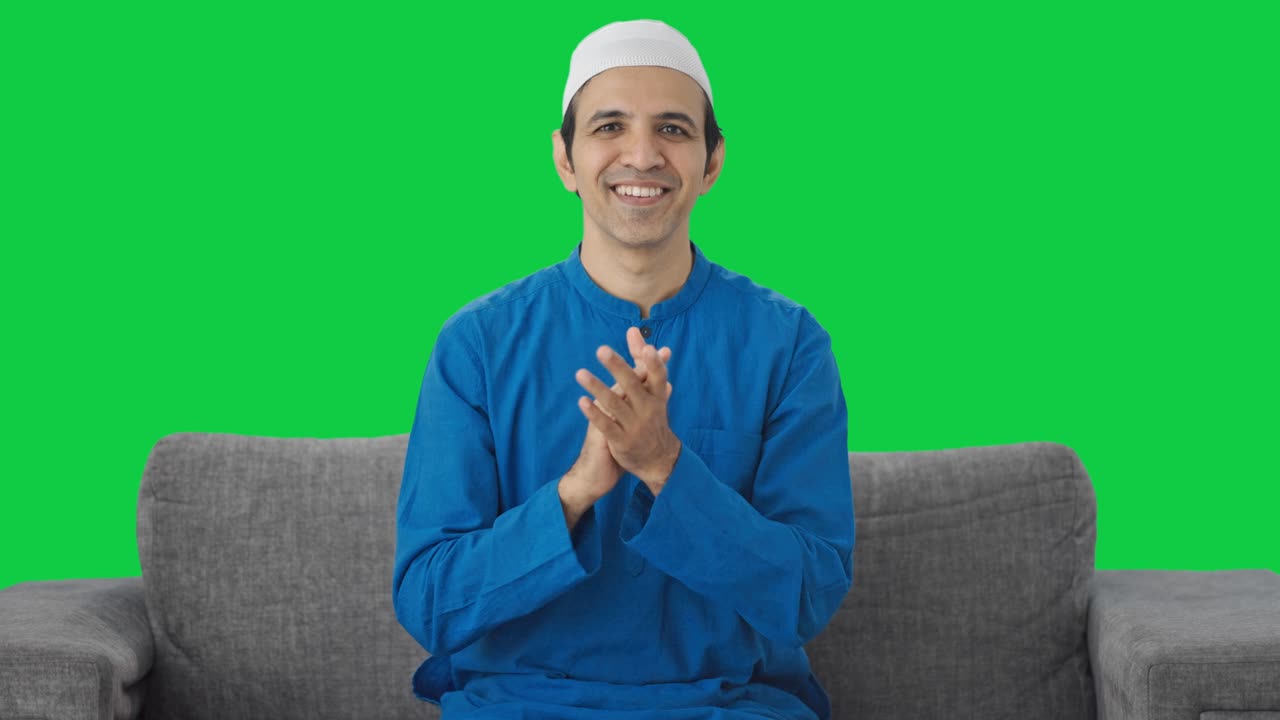 행복한 무슬림 남자가 박수를 치고 녹색 화면을 높이 평가합니다.