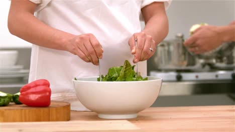 una pareja preparando ensalada.