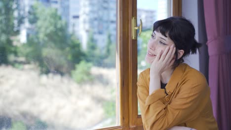 at the window the young woman is daydreaming and laughing.