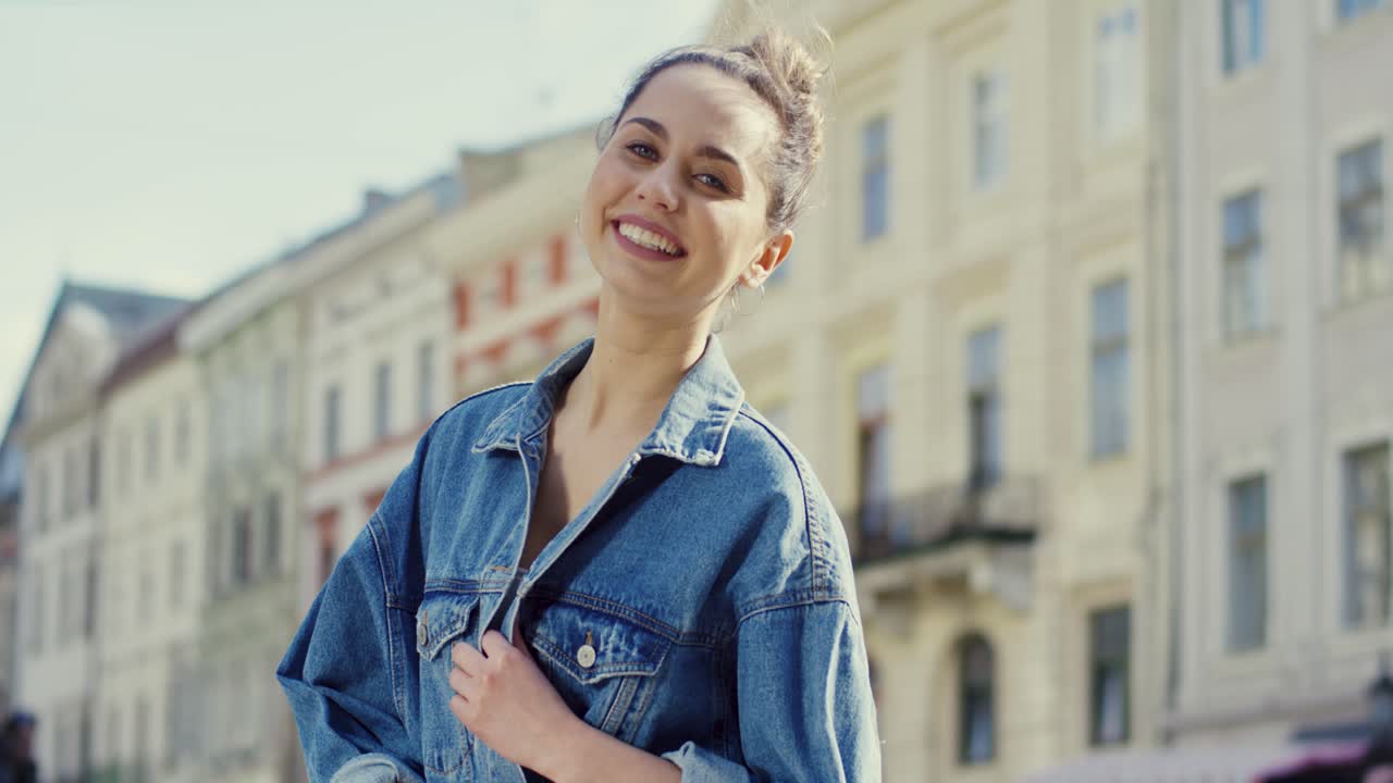 retrato de una mujer encantadora sonriendo mientras está de pie en el centro de una ciudad