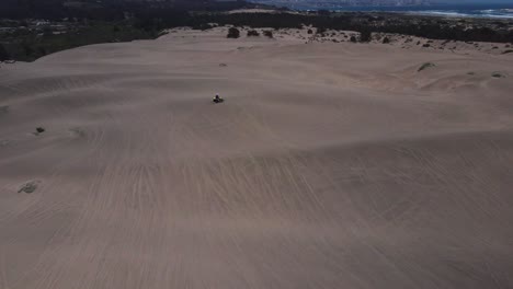 aerial view of person riding quad bike on sand dunes