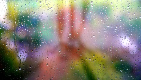 droplets of water on enlighted colored glass background. rain water drops running down. water droplets falling on glass surface.