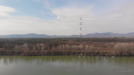 Ascending-aerial-shot-at-an-electric-tower,-with-mountains-in-the-background---energy-concept