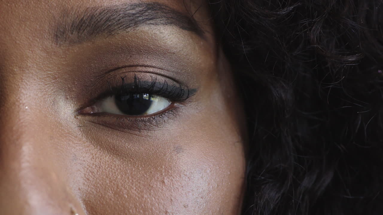 close up macro of african american woman eye blinking looking at camera