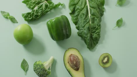 video de aguacate fresco, brócoli, pimienta verde, manzana y hojas verdes sobre un fondo verde