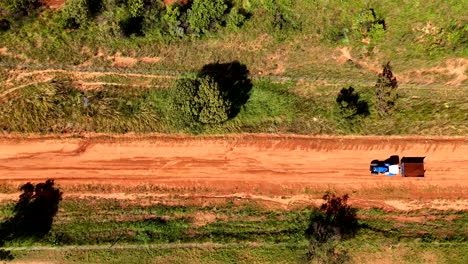 tractor hauling soil on a dirt road, seen from above, with a focus on the natural surroundings