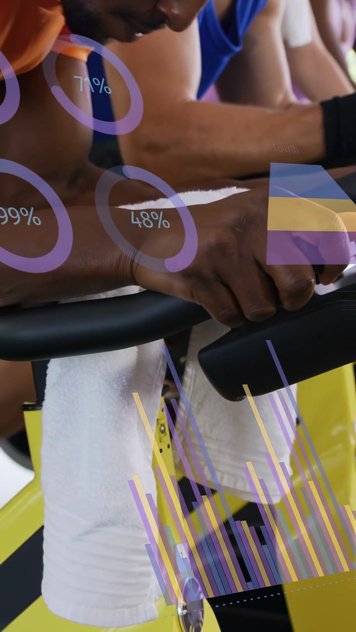 Spin riders leaning forward, gripping handlebars, pedaling on bikes in gym with consoles and charts