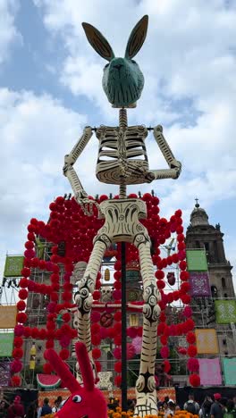 tall mexican skeleton sculpture with offering behind during day of the dead festival in daylight