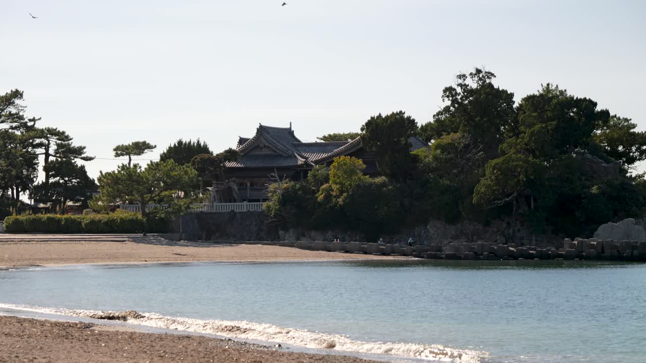 un paisaje tranquilo en una playa abierta con un santuario japonés en la distancia