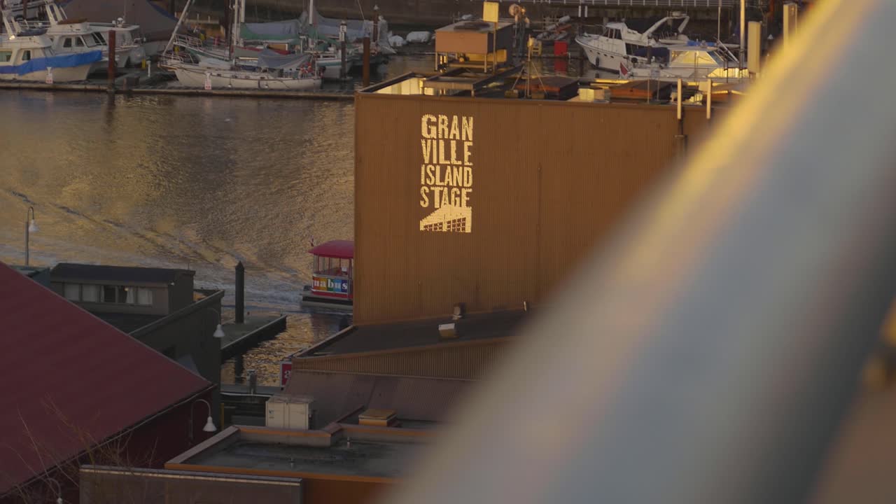 Panoramic shot of the Granville Island Water Taxi at dusk doing its regular tour with its calm surrounding waters and the cityscape in the background