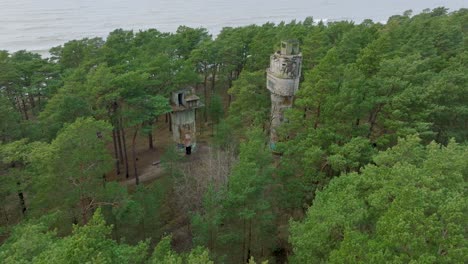 establishing aerial view of old soviet military concrete observation watchtower, pine tree forest, liepaja , military heritage, nordic woodland, wide drone shot moving forward, tilt down