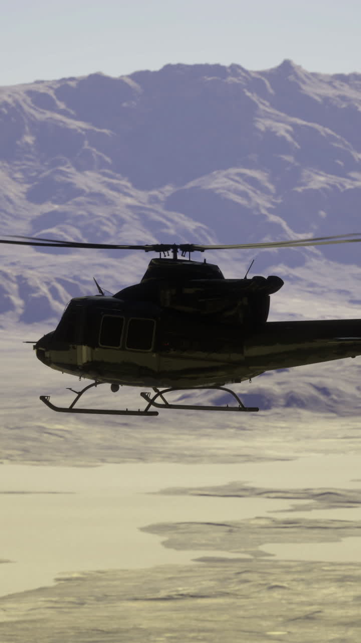 Military helicopter flies over desert landscape with mountains in background