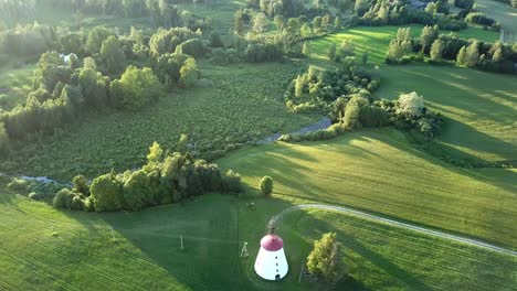 windmill in the middle of the field in latvia on a sunny morning - ascending drone shot