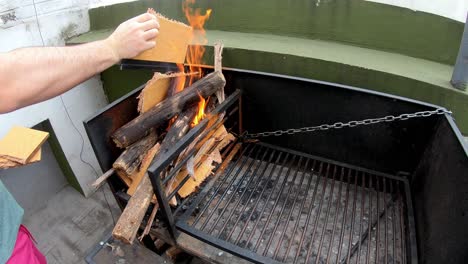 Video-Eines-Weißen-Mannes,-Der-An-Einem-Sonnigen-Tag-Mit-Pappe-Das-Feuer-Zum-Grillen-Anzündet