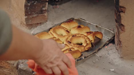 freshly baked paraguayan chipa coming out of the tatakua, a traditional paraguayan clay oven